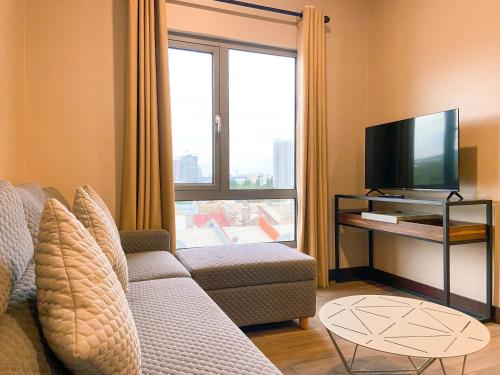 a living room with a couch and a flat screen tv at Staycity Serviced Apartment in Cebu City