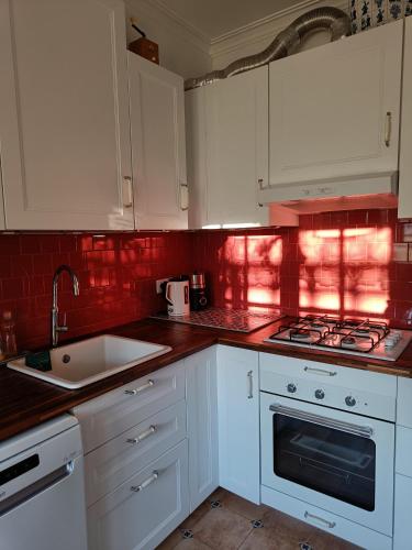 a kitchen with white cabinets and red tiles at Casa Flow and Glow in Santiago do Cacém