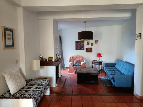 a living room with a blue couch and a chair at Casa Flow and Glow in Santiago do Cacém