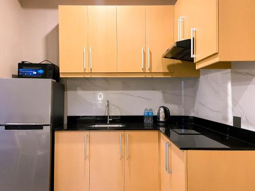 a kitchen with wooden cabinets and a sink and a refrigerator at Staycity Serviced Apartment in Cebu City