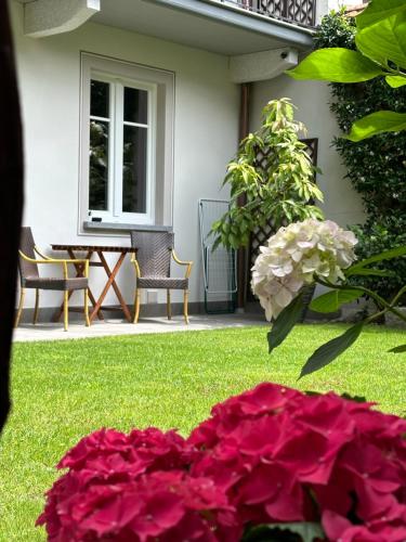 a garden with pink flowers and a table and chairs at Garden Lodge in Stresa