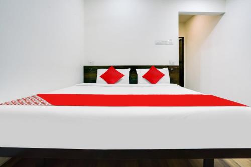 a white bed with red pillows in a room at Hotel O White Villa in Nagpur