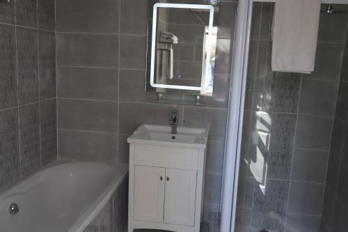 a bathroom with a sink and a tub and a mirror at Lakeview Boutique Hotel & Conference Center in Benoni