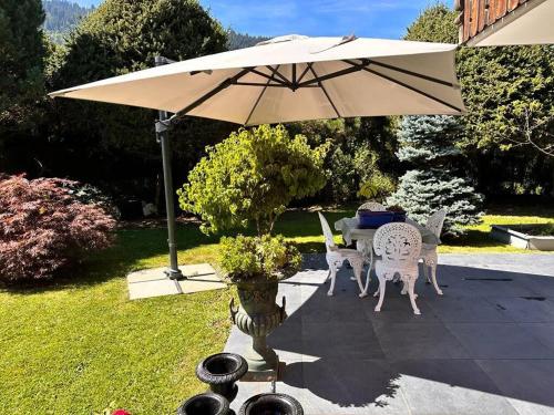 a table and chairs under an umbrella in a yard at 3 BR Classic Chalet in Gstaad By Smiling House in Gstaad