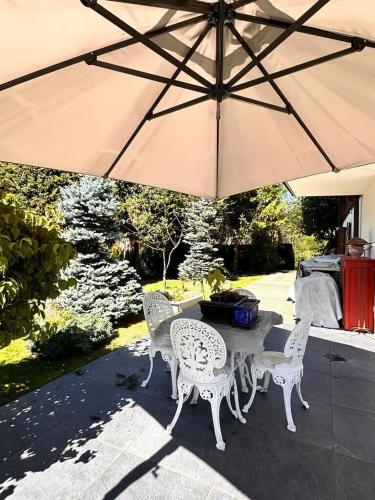 a table and chairs under a large umbrella at 3 BR Classic Chalet in Gstaad By Smiling House in Gstaad