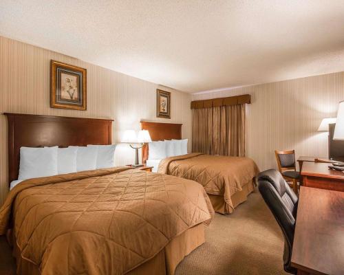 ein Hotelzimmer mit zwei Betten und einem Schreibtisch in der Unterkunft Quality Inn & Conference Centre in Red Deer