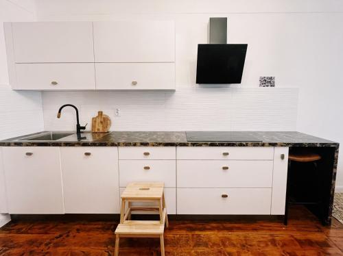 a kitchen with white cabinets and a sink and a stool at Cozy flat in Center in Maribor