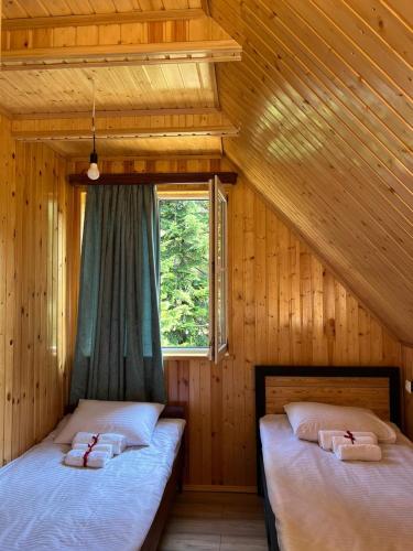 two beds in a wooden room with a window at Panorama Gomismta in Gomi