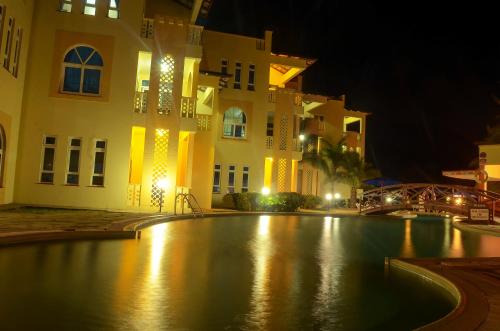 a swimming pool in front of a building at night at Azul Margarita Beach Resort in Bamburi