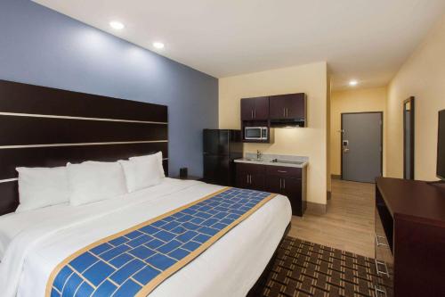 a hotel room with a large bed and a kitchen at Days Inn by Wyndham Baton Rouge Airport in Baton Rouge