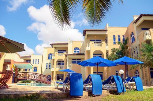 a resort with chairs and umbrellas in front of a building at Azul Margarita Beach Resort in Bamburi