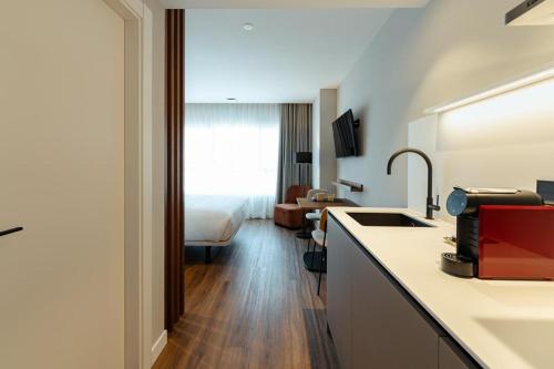 a kitchen with a sink and a room with a bed at Apartamentos 2H LIVING in León