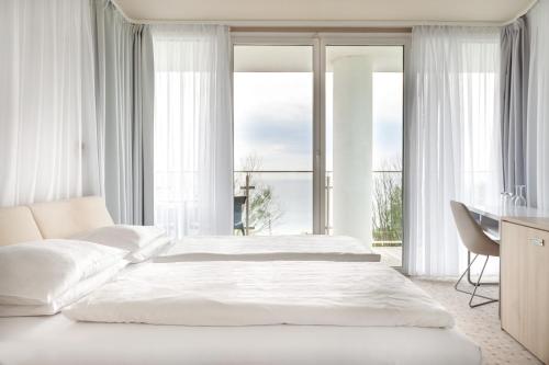 a white bedroom with a large bed and a desk at Ultra Marine by Zdrojowa in Kołobrzeg
