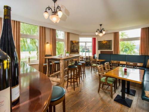 a restaurant with tables and chairs and a bottle of wine at Peters - das Genusshotel in der Wingst in Wingst