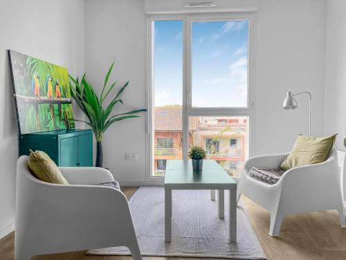 un salon avec deux chaises et une table et une fenêtre dans l'établissement Appartement Elégant à Deux Pas du Capitole, à Toulouse