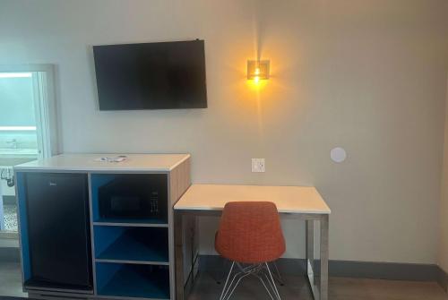 a desk with a chair and a tv on a wall at Super 8 by Wyndham Oceanside Downtown in Oceanside