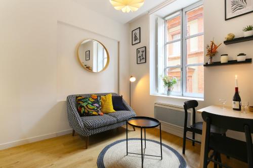 un salon avec une chaise et un miroir dans l'établissement Le Chalande - Hyper Centre, à Toulouse