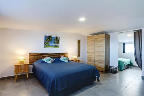 ein Schlafzimmer mit einem blauen Bett in einem Zimmer in der Unterkunft Duplex Bellevue - Entre Mer et Montagne - Meublé Classé 3 Etoiles in Le Tampon