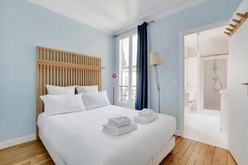 une chambre avec un lit blanc avec des serviettes dessus dans l'établissement Pick A Flat's Apartment in Ternes - Arc de Triomphe, à Paris