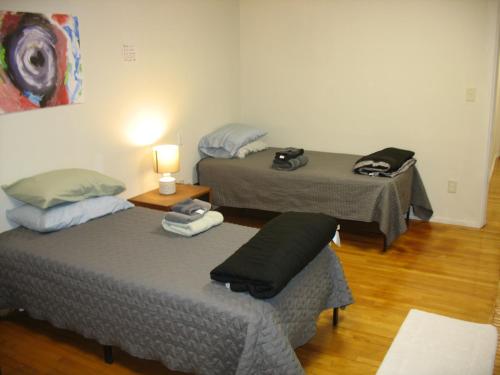 two beds in a room with a lamp on a table at Art Gallery Hostel in Whitefield