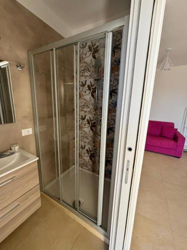 una doccia in vetro in bagno con divano rosa di Le Casette del Porto di Sciacca a Sciacca