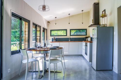 une cuisine avec une table, des chaises et un réfrigérateur dans l'établissement La cabane du pont du Douet, à Mazières-de-Touraine