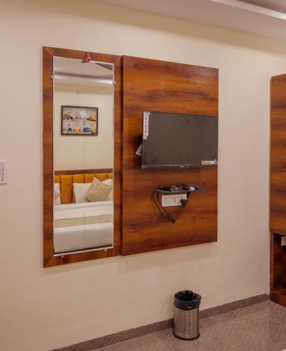 a mirror hanging on a wall with a tv at Hotel Dream Inn in Mānglia
