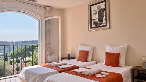 deux lits dans une chambre avec une grande fenêtre dans l'établissement Villa Les Pariades : 8 Prs, 4 ch, Piscine, Vue mer, à Vallauris