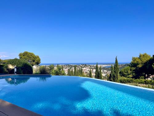 une grande piscine bleue avec une ville en arrière-plan dans l'établissement Villa Les Pariades : 8 Prs, 4 ch, Piscine, Vue mer, à Vallauris