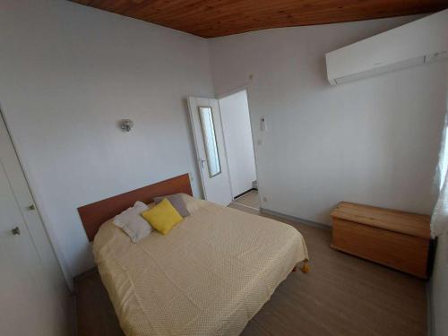 - une chambre avec un lit et un oreiller jaune dans l'établissement Duplex climatisé 6 pers, terrasse sud, proche plage, parking privé - FR-1-326-662, à Le Castellas