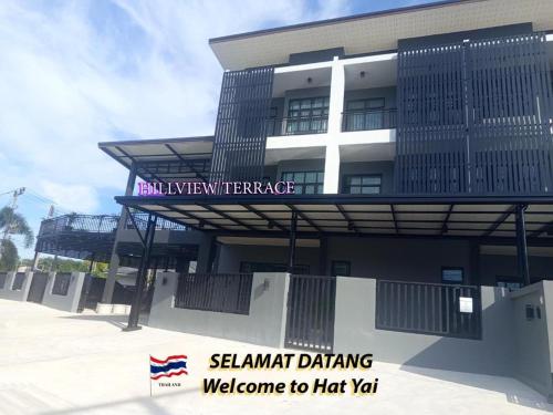 a building with a sign that reads shanghai drinking welcome to had yard at Hillview Terrace in Hat Yai