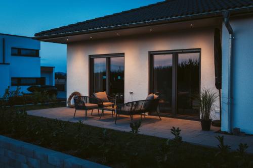 a patio with chairs and a table in front of a house at Hunsrück Lodge in Mittelstrimmig
