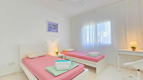two beds in a white room with pink sheets at CSS Cute Superior King's Palace in Paphos City