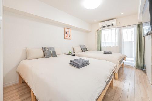 two beds in a room with white walls at 新宿市中心歌舞伎客房源出行便利免费Wi-Fi in Tokyo