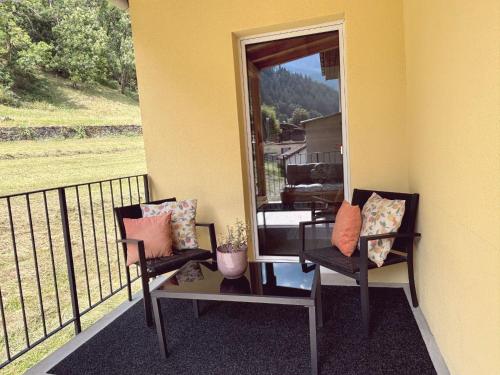 a balcony with two chairs and a mirror at Family apartment in Poschiavo