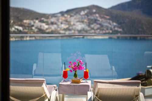 a table with two chairs and flowers on a balcony at Rhapsody Hotel & Spa Kalkan in Kalkan