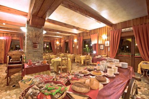 una grande sala da pranzo con tavoli con sopra cibo di Hotel Astoria a Courmayeur