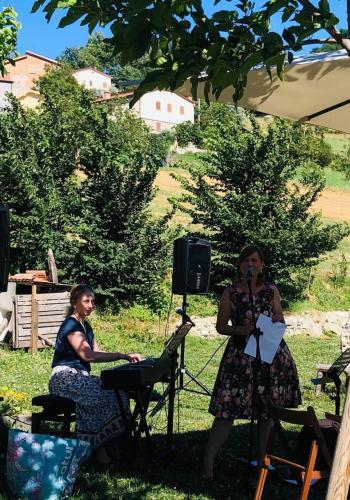 two women standing in the grass with a microphone at B&B EcoAntico casa in paglia in Maiolo