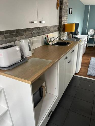 a kitchen with white cabinets and a counter top at Birkdale's Hidden Gem in Southport