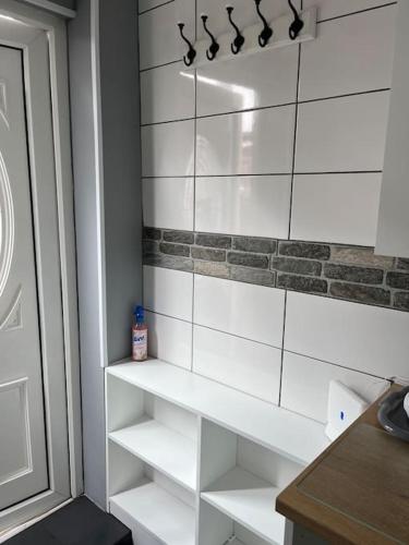 a bathroom with white tiled walls and white shelves at Birkdale's Hidden Gem in Southport