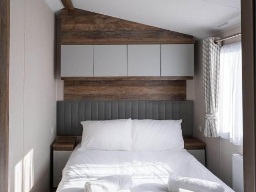 a bedroom with a white bed with a wooden headboard at Pinewoods Park Classic no.1 - sleeps 6 – no dogs in Wells next the Sea