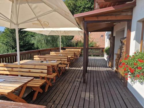a row of wooden tables and umbrellas on a deck at Wellness hotel Chata Jana in Lopeník