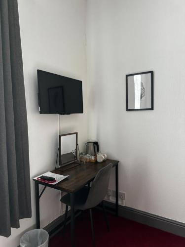 a room with a desk with a tv on the wall at The Derby Hotel in Barrow in Furness