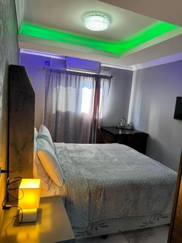 a bedroom with a bed with green lights on it at Ekuthuleni Guest House Benoni in Benoni