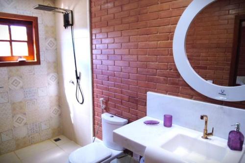 a bathroom with a white sink and a brick wall at Casas perto cervejaria 3 Santas in Santa Teresa