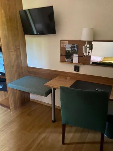 a room with a table and a bench and a tv at Home Hotel Kung Oscar in Trollhättan