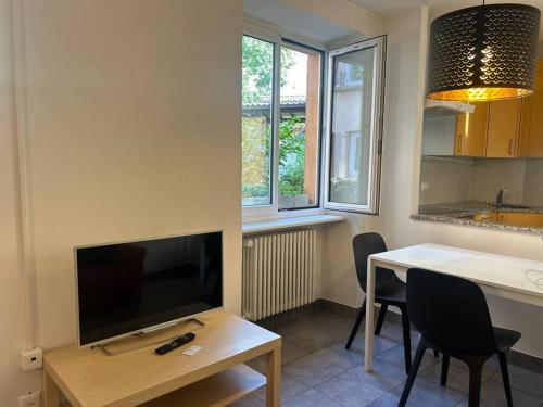 a living room with a television and a table with chairs at Davesco Court Apartment in Cadro