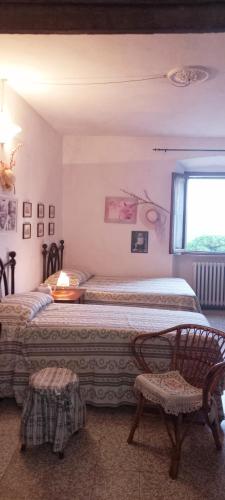 a bedroom with two beds and a window and a chair at La Casa del Gallo in Radicondoli