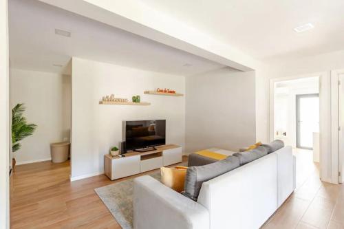 a living room with a white couch and a television at Casa do Tourão - Ponte de Lima in Ponte de Lima