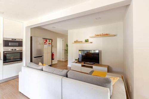 a living room with a white couch and a kitchen at Casa do Tourão - Ponte de Lima in Ponte de Lima